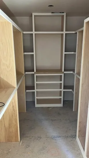 Custom walk-in closet framing with built-in shelving and open compartments.