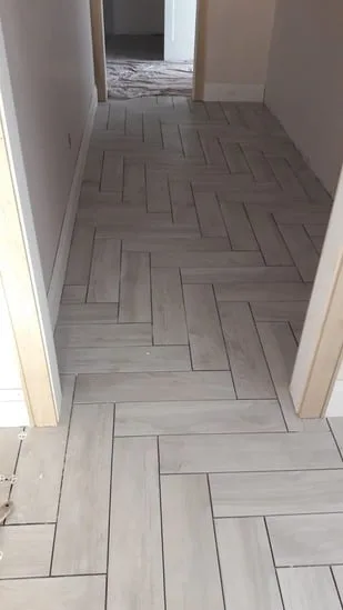 Herringbone tile floor installation with aligned pattern in hallway.