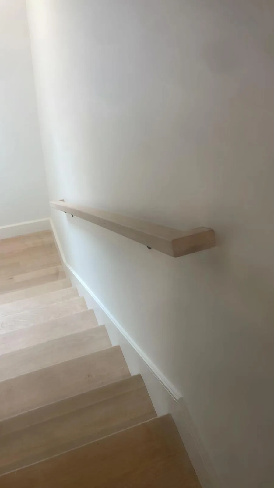 Wood stair handrail installation with clean wall-mounted alignment.