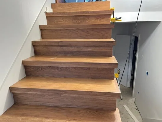 Wood stair tread installation in progress with uniform step layout.